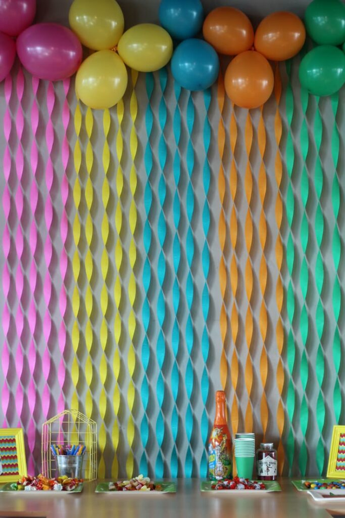 Enfeite com fitas e balões coloridos na parede