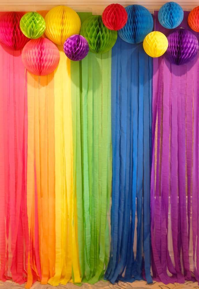 Parede com fitas e enfeites de papel em vermelho, laranja, amarelo, verde, azul e roxo
