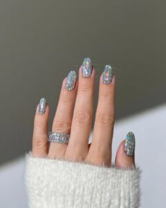 Mão de pele clara, com anel de brilhando e unha amendoada com glitter estilo disco ball