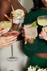 Mãos de diferentes mulheres segurandos copos de drinks.