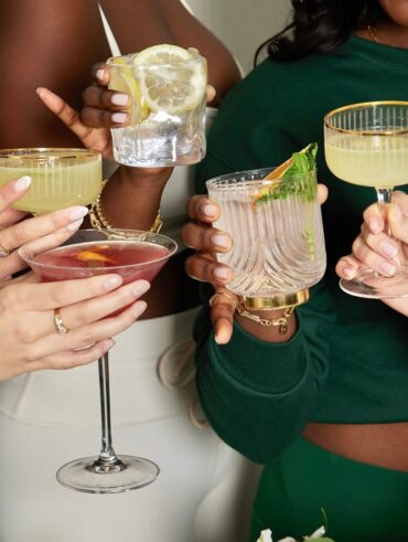 Mãos de diferentes mulheres segurandos copos de drinks.