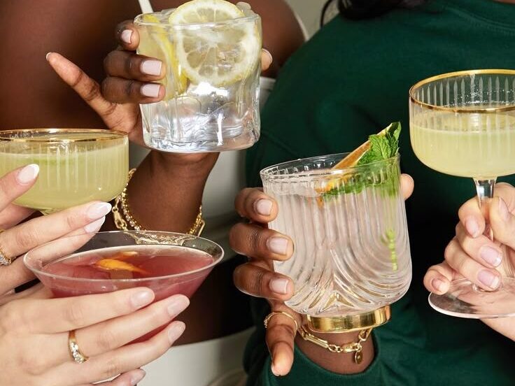 Mãos de diferentes mulheres segurandos copos de drinks.