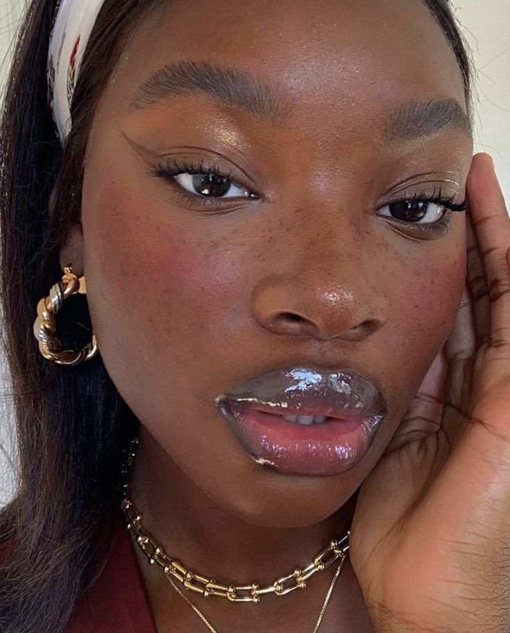 Mulher de pele preta, com acessórios em dourado e glossy lips