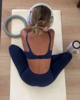 Mulher de pele clara, com calça e top azul marinho e coque