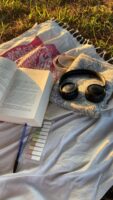 Livro, fone e caneta sobre a grama