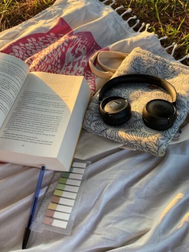 Livro, fone e caneta sobre a grama