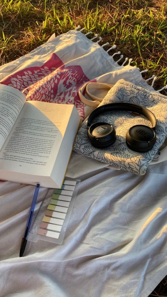 Livro, fone e caneta sobre a grama