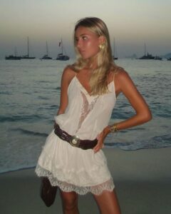Mulher de pele clara, com look branco boho e cabelo loiro
