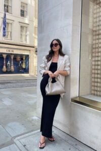 Mulher de pele clara, com blazer e bolsa neutro e chinelo de dedo