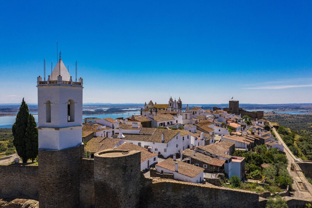 Paisagem com torres e casas brancas com lago e céu azul ao fundo