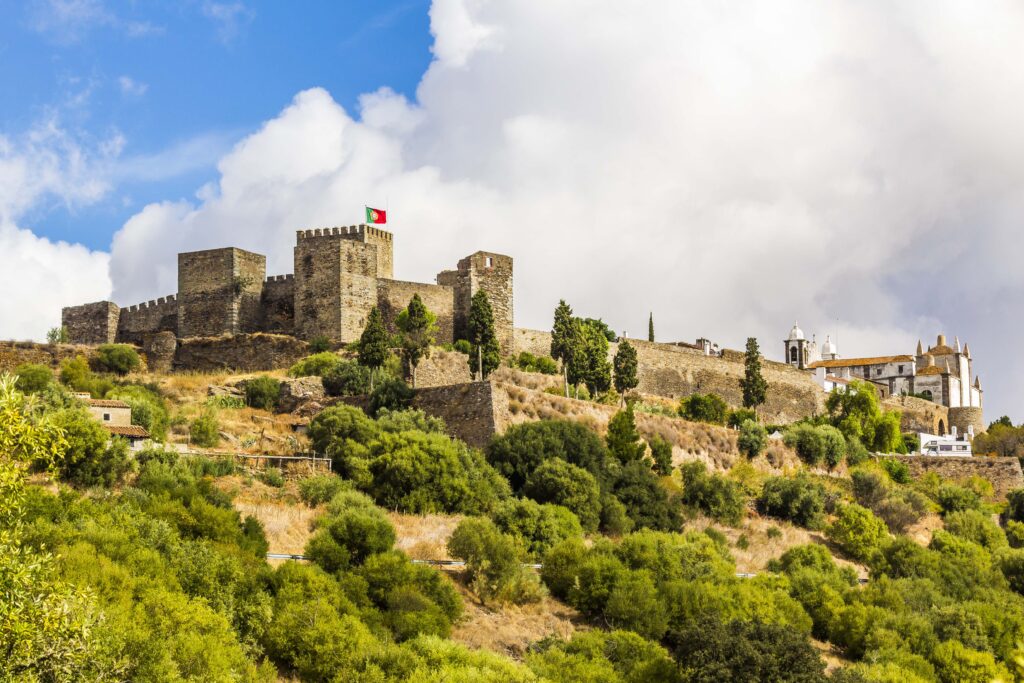 Castelo medieval ao fundo com céu azul e verde