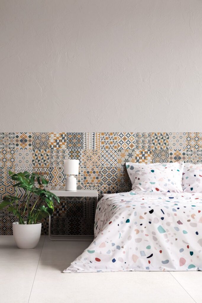Quarto com azulejos ou papel de parede na cabeceira, roupas de cama com estampa de granilite