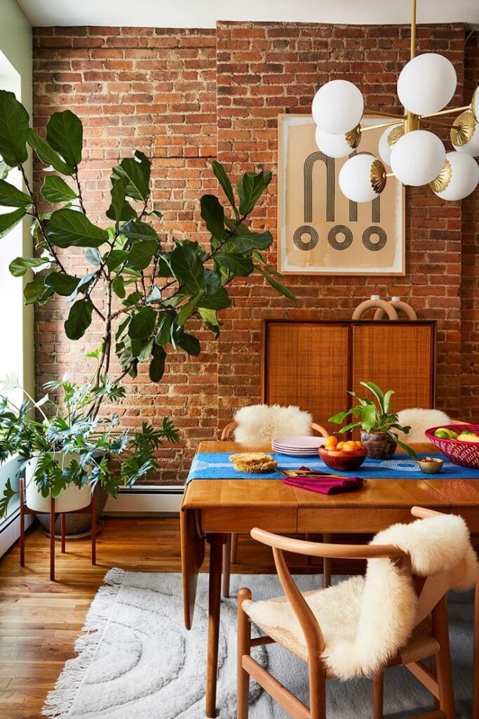 Espaço com plantas, paredes de tijolinhos, mesa e móveis de madeira