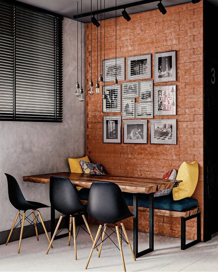 Sala de jantar com parede de tijolinhos e quadros, mesa de madeira e cadeiras pretas