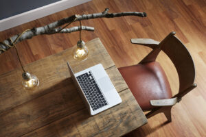 Mesa de madeira com notebook e cadeira de madeira com assento em couro terracota