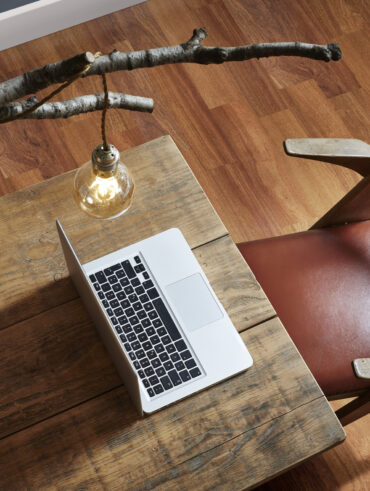 Mesa de madeira com notebook e cadeira de madeira com assento em couro terracota