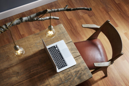 Mesa de madeira com notebook e cadeira de madeira com assento em couro terracota