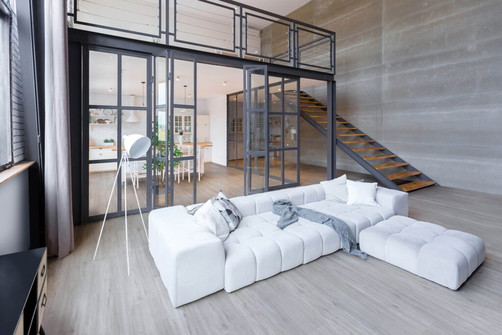 Sala com sofá branco, aberturas em cinza-escuro e luminária de piso branca