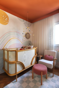 Quarto de bebê com berço, poltrona e pufe, e teto na cor Tamarindo
