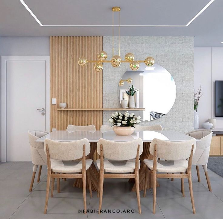 Sala de jantar com mesa retangular com tampo claro, cadeiras estofadas neutras, pendentes dourados e espelho redondo