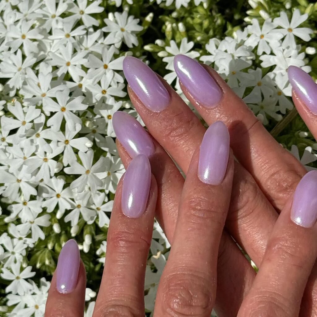 Mãos de pele clara, com unha amendoada lavanda com acabamento perolizado 