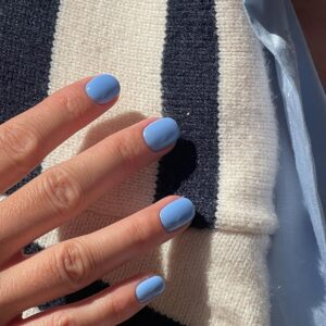 Mão de pele clara, com unha curta squoval azul-bebê