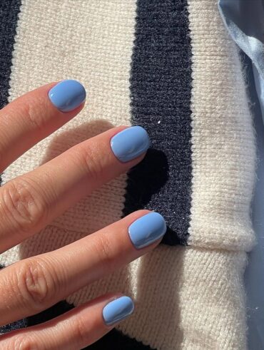 Mão de pele clara, com unha curta squoval azul-bebê