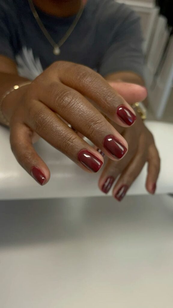Mãos de pele preta, com unha curta e quadrada pintada em esmalte vermelho-cereja