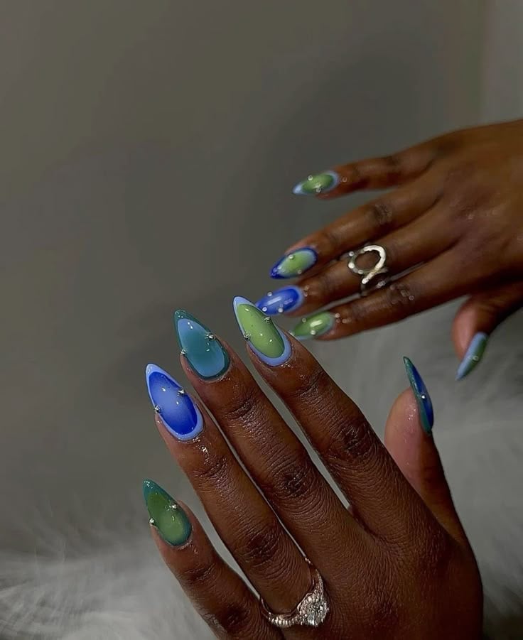 Mãos de pele prea, com unha amendoada azul e verde, com design aura e tachas