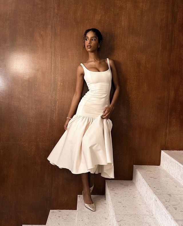 Mulher de pele preta, com vestido branco com saia ampla 