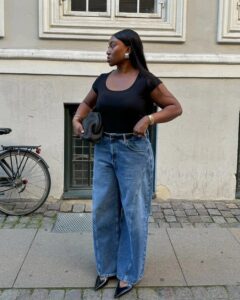 Mulher jovem com blusa preta, calça jeans e cinto