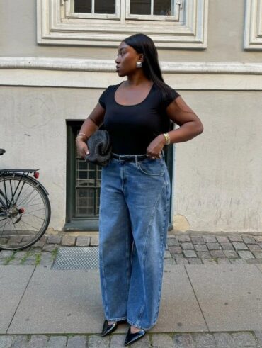 Mulher jovem com blusa preta, calça jeans e cinto