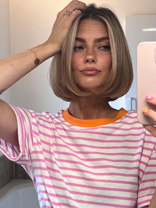 Mulher de pele clara, com blusa listrada e cabelo loiro cup bob