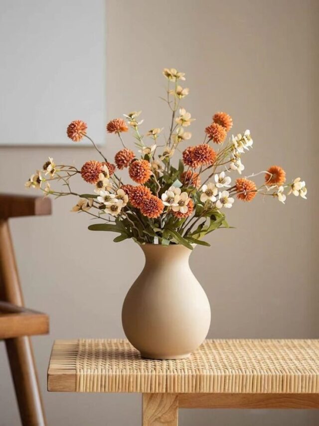 Vaso orgânico bege em cima de banco com flores secas