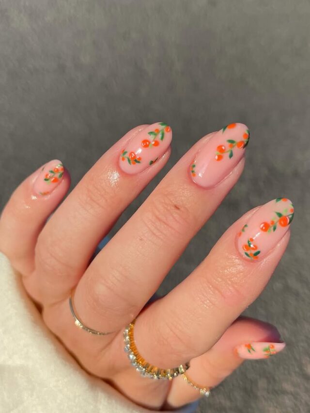 Mão de pele branca com esmaltação em gel na cor laranja, com nail art com frutas e laranjas