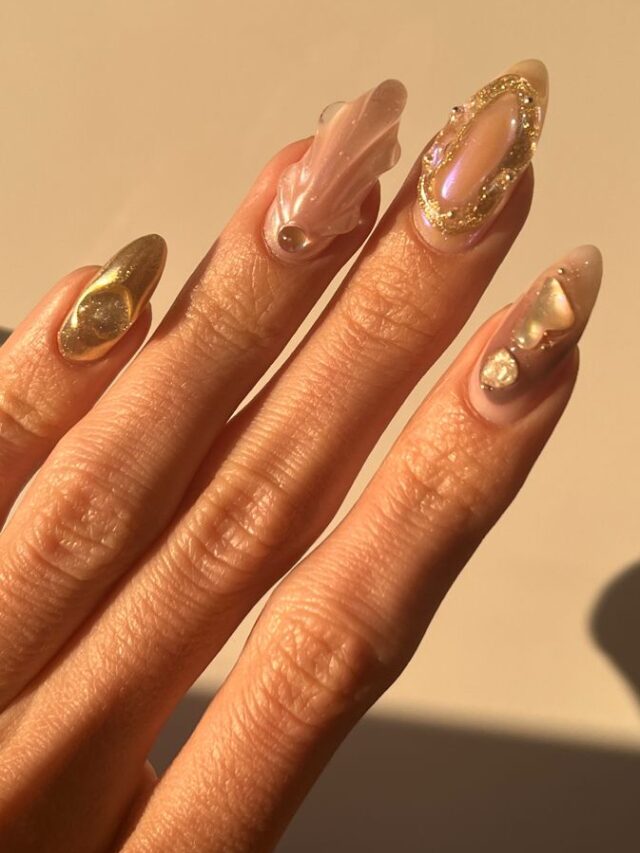 Mão de pele clara, com unha amendoada perolada com detalhes em gel e em dourado