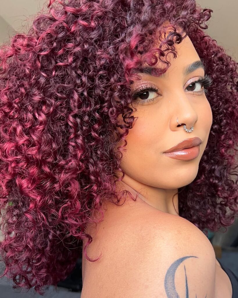 Mulher de pele preta clara, com cabelo crespo cherry cola 