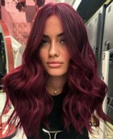 Mulher de pele clara, com blusa preta e cabelo cherry cola