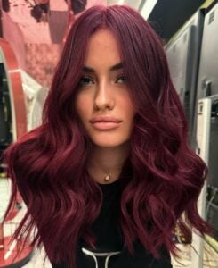 Mulher de pele clara, com blusa preta e cabelo cherry cola