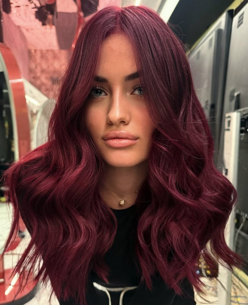 Mulher de pele clara, com blusa preta e cabelo cherry cola 