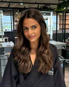Mulher negra com cabelo liso e longo, com morena iluminada na cor mocha mousse