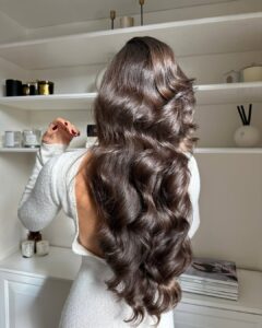 Mulher de pele clara, com vestido branco e cabelo castanho hidratado
