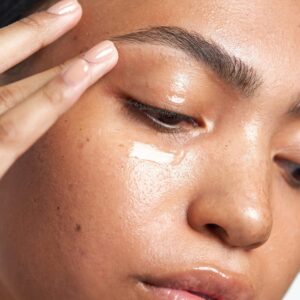Mulher de pele clara, com creme aplicado na área dos olhos