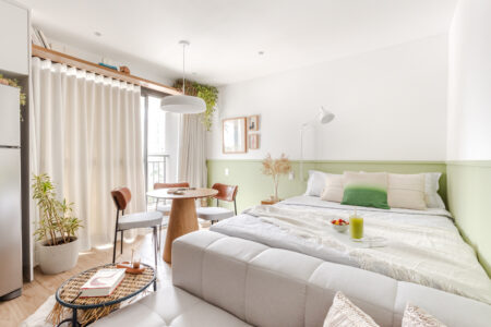 Quarto de casal com paleta de cores neutras e meia parede verde-claro
