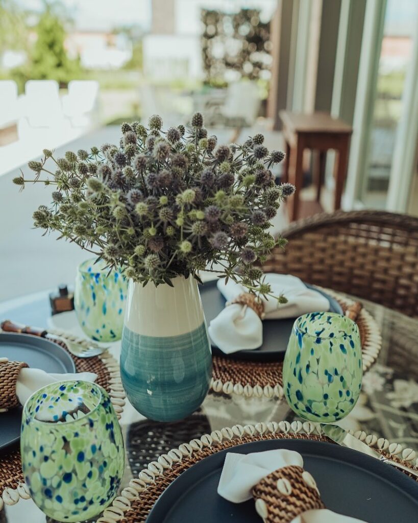 Mesa posta com vaso branco e azul com flores secas e copos pintados