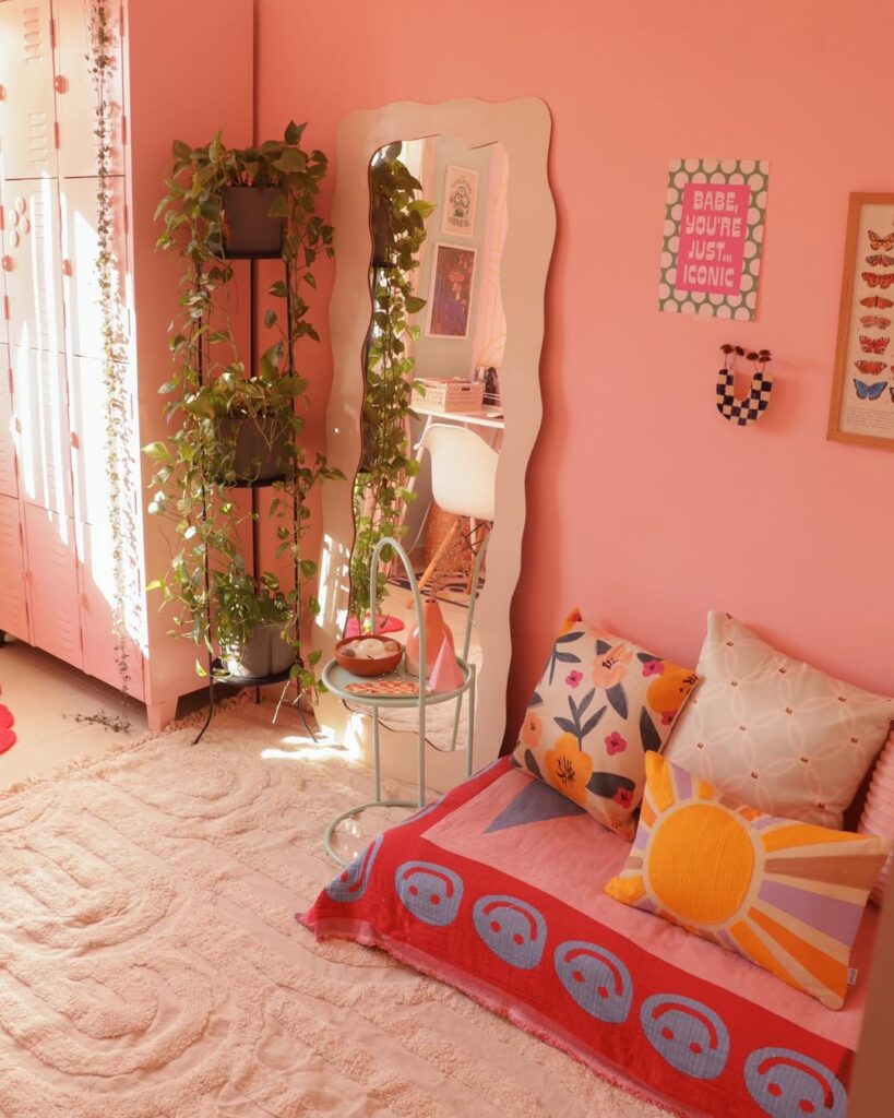 Ambiente com parede rosa, espelho comprido orgânico e plantas no canto