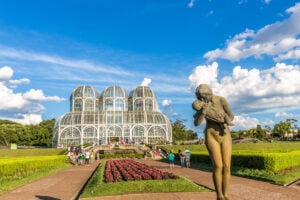 Paisagem com céu azul e em primeiro plano uma escultura de uma mulher segurando um bebê