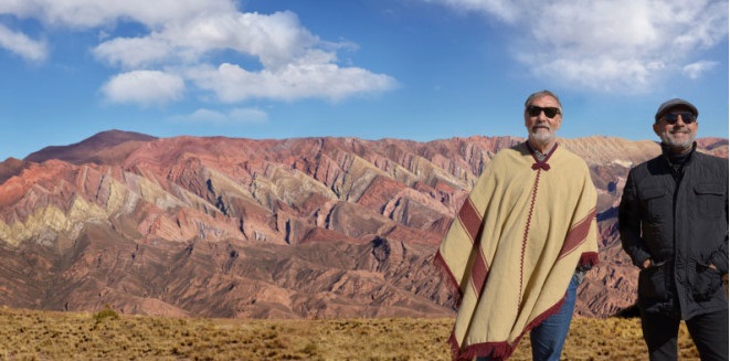 Dois homens em pé diante de montanhas e céu azul