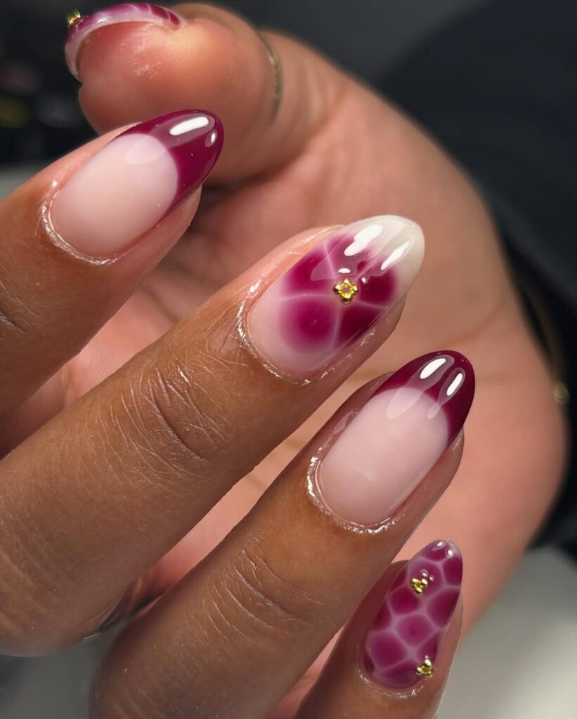 Mão de pele preta, com unha amendoada com francesinha vermelho cereja e padrões geométricos