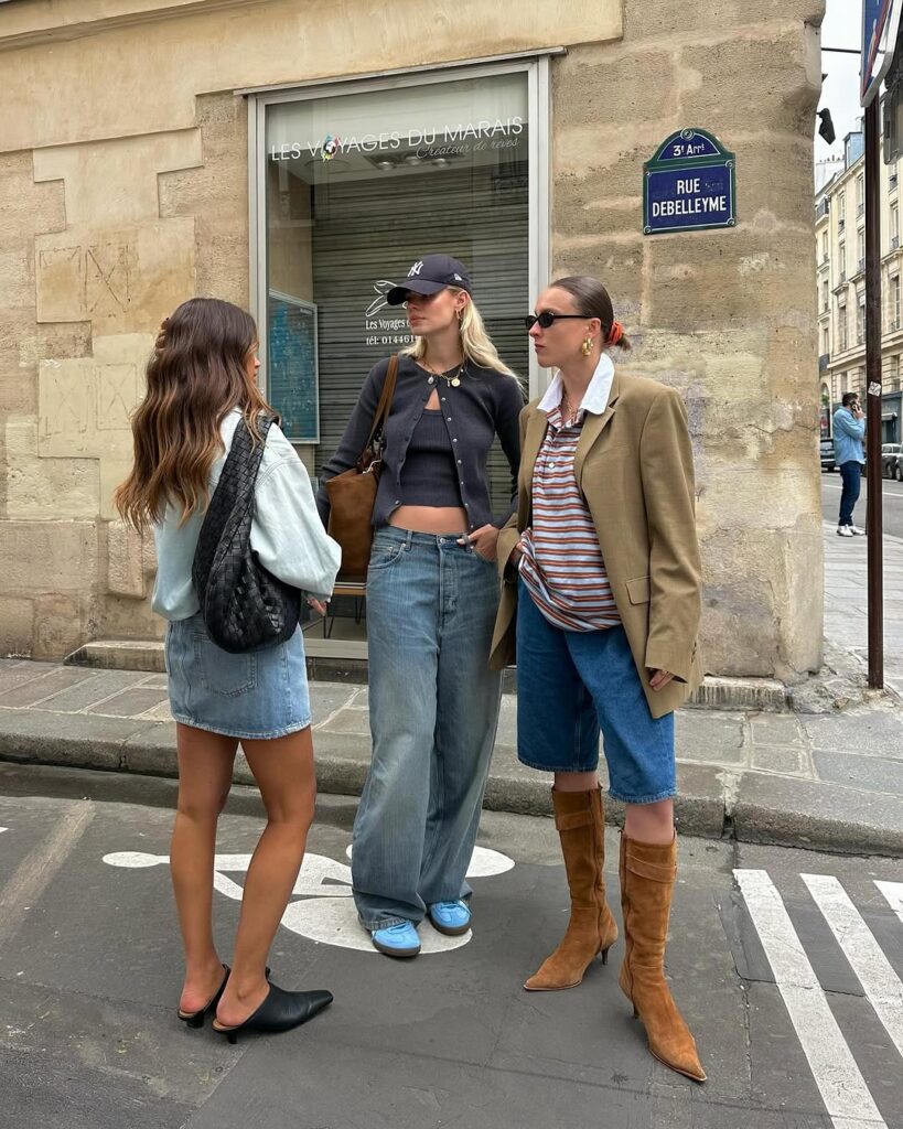foto com 3 mulheres jovens e magras no meio da rua. Elas usam look de outono com roupas em tons neutros.